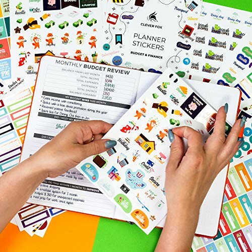 Hands arranging planner stickers on a budget review page.